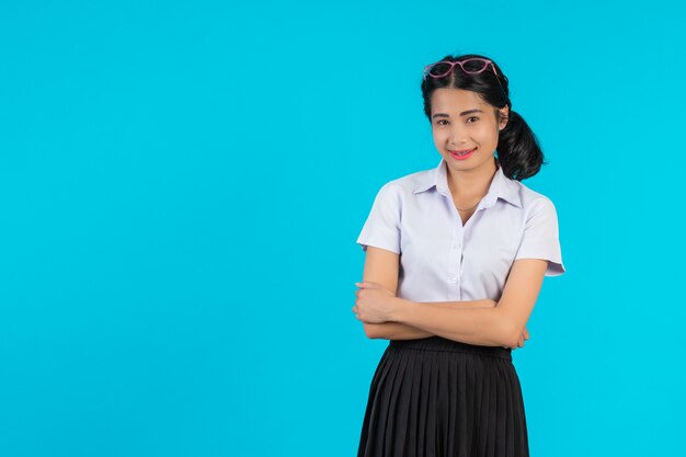 Asiatische Studentinnen, die in den verschiedenen Positionen auf einem Blau aufwerfen.