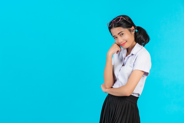 Asiatische Studentinnen, die in den verschiedenen Positionen auf einem Blau aufwerfen.