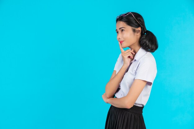 Asiatische Studentinnen, die in den verschiedenen Positionen auf einem Blau aufwerfen.