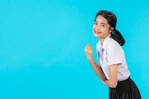 Asiatische Studentinnen, die in den verschiedenen Positionen auf einem Blau aufwerfen.