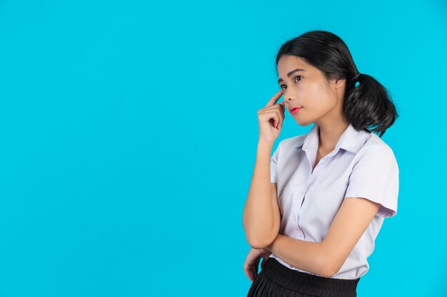 Asiatische Studentinnen, die verschiedene Gesten auf einem Blau durchführen.