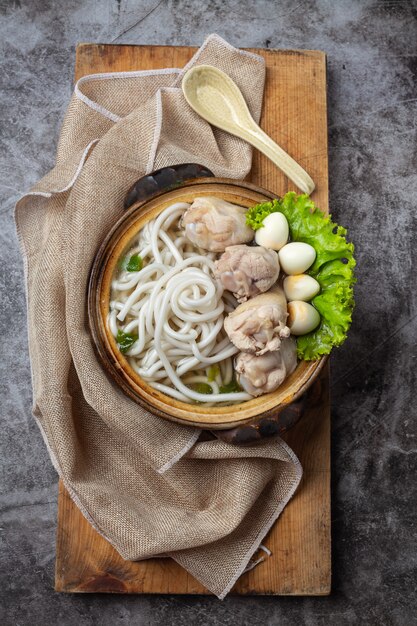 Asiatische Suppe mit Nudeln, Schweinefleisch und Frühlingszwiebeln dicht in einer Schüssel auf dem Tisch.