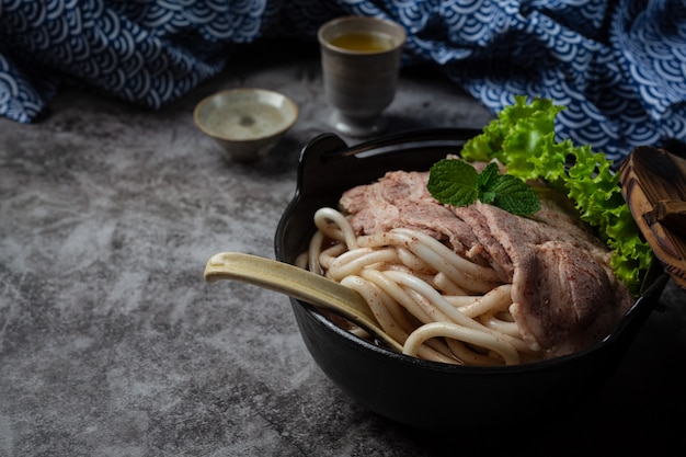 Kostenloses Foto asiatische suppe mit nudeln, schweinefleisch und frühlingszwiebeln dicht in einer schüssel auf dem tisch.