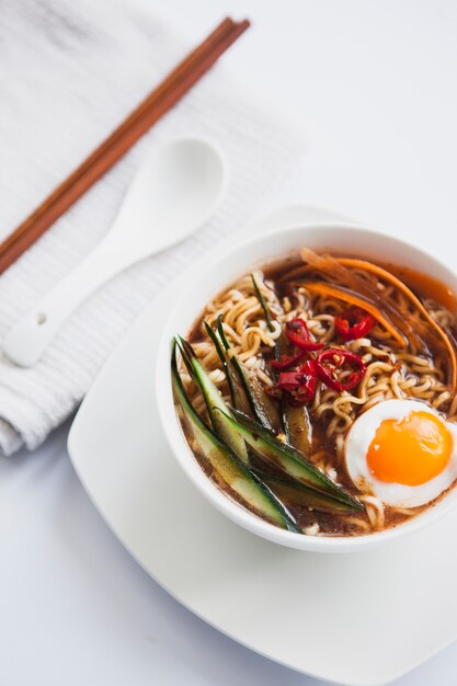 Asiatische Suppe nahe Löffel und Essstäbchen