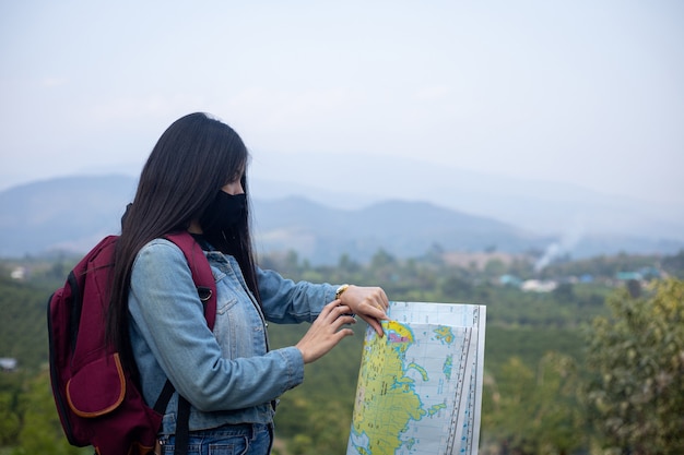 Asiatische Touristin mit Gesichtsmaske, die auf die Armbanduhr schaut