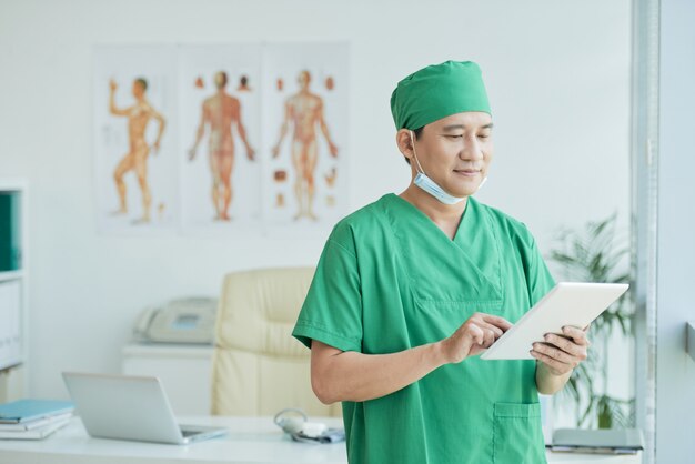 Asiatischer Doktor Wearing Green Uniform, das horizontale Taille herauf Porträt bearbeitet