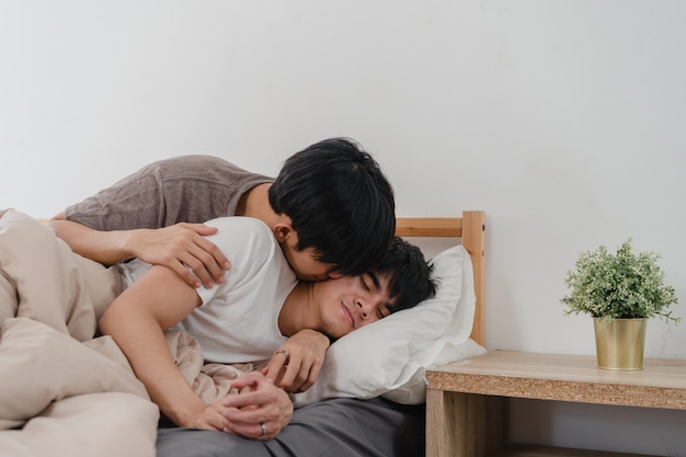 Asiatischer homosexueller paarkuß und -umarmung auf bett zu hause. die jungen asiatischen glücklichen lgbtq-männer entspannen sich rest verbringen zusammen romantische zeit, nachdem sie morgens im schlafzimmer zu hause aufwachen.