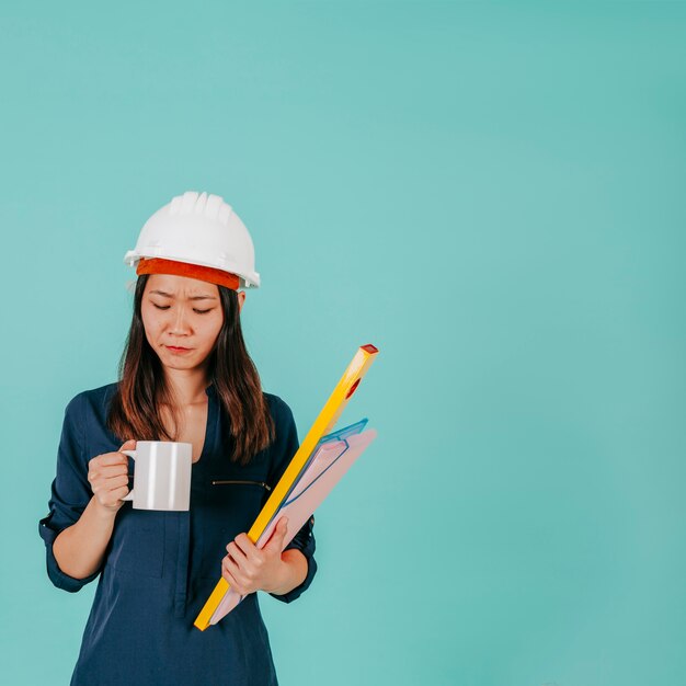 Asiatischer Ingenieur, der Becher betrachtet