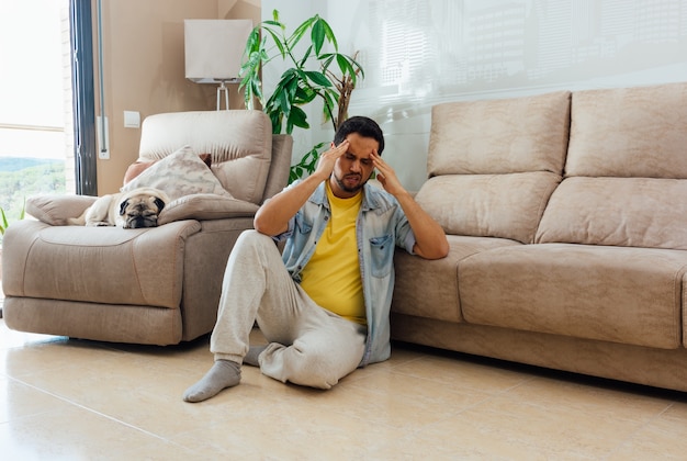 Asiatischer junger Mann mit Depression, die zu Hause auf dem Boden sitzt