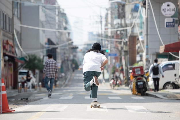 Asiatischer Mann, der draußen Skateboard fährt