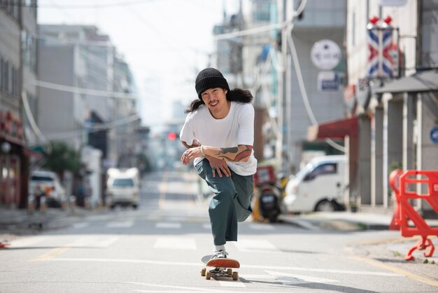 Asiatischer Mann, der draußen Skateboard fährt