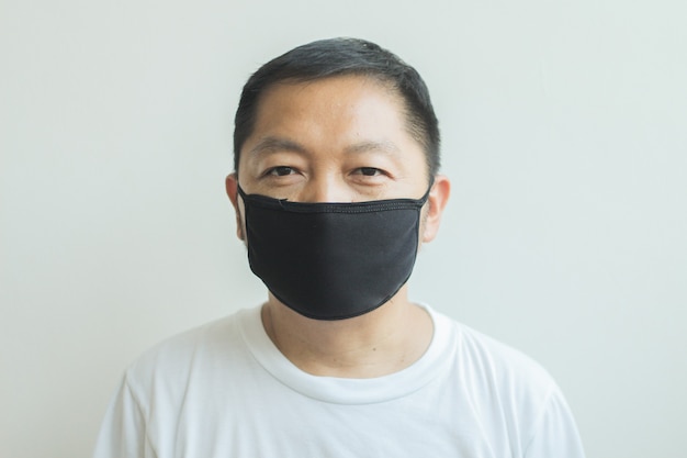 Asiatischer Mann, der eine schwarze medizinische Maske trägt