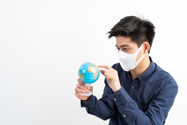 Asiatischer Mann, der Gesichtsmaske hält Karte der Globus-Weltkarte in der Hand hält