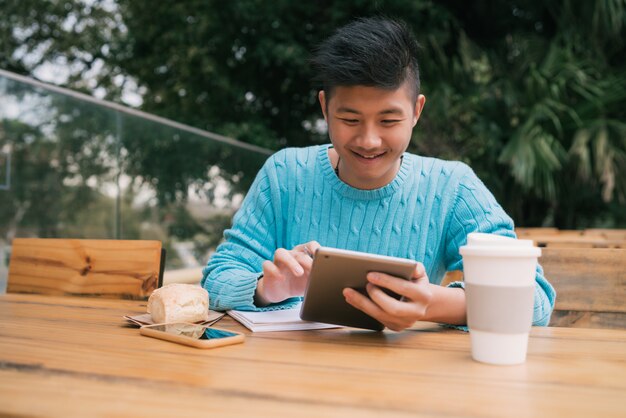 Asiatischer Mann, der im Kaffeestube studiert