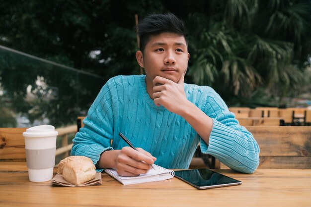 Asiatischer Mann, der im Kaffeestube studiert.