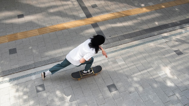 Asiatischer Mann, der in der Stadt Skateboard fährt