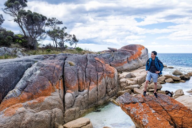 Asiatischer Mann posiert in Bay of Fire in Tasmanien, Australien