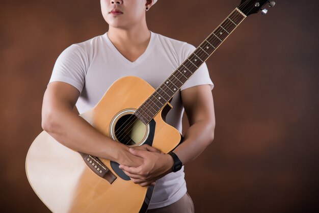 Asiatischer Musiker des jungen Mannes mit Akustikgitarre