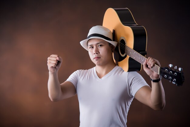 Asiatischer Musiker des jungen Mannes mit Akustikgitarre