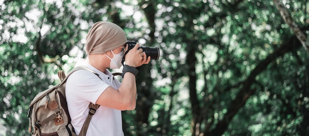 Asiatischer Reisender mit Rucksack, der ein Foto im Park mit Kopienraum macht Reisefotograf Berufungs- und Urlaubskonzept