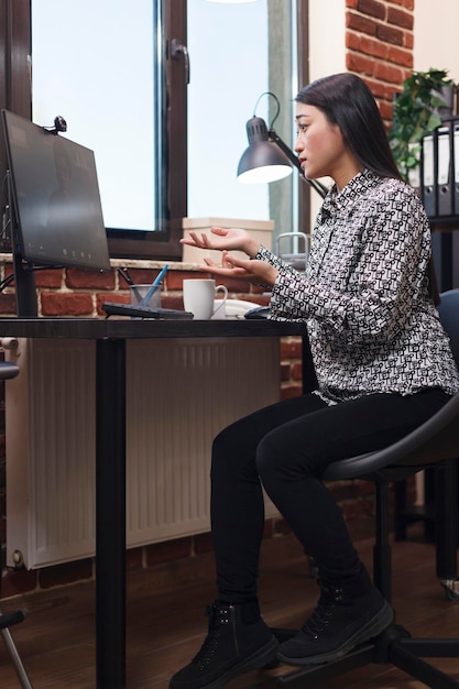 Asiatischer Teamleiter in Remote-Online-Videoanruf mit Agenturkollege. Marketingagentur beschäftigter asiatischer Teamleiter in Internet-Fernkonferenz mit afroamerikanischem Bürokollegen.