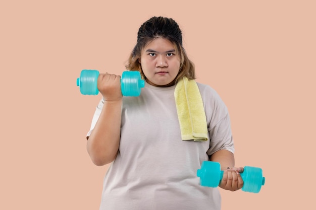 Asiatisches großes Mädchen, das Fitnessübungen mit isolierten Hanteln macht
