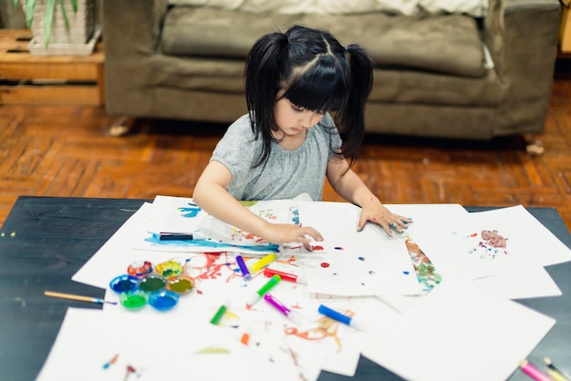 Asiatisches Kindermädchen spielt Malerei mit Glück und Freude