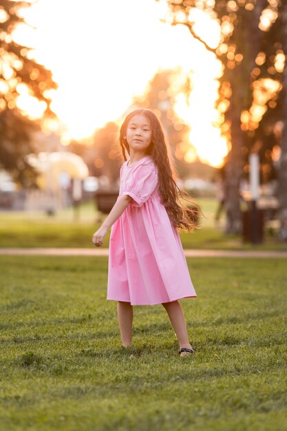 Asiatisches kleines Mädchen mit langen Haaren, die im Park gehen