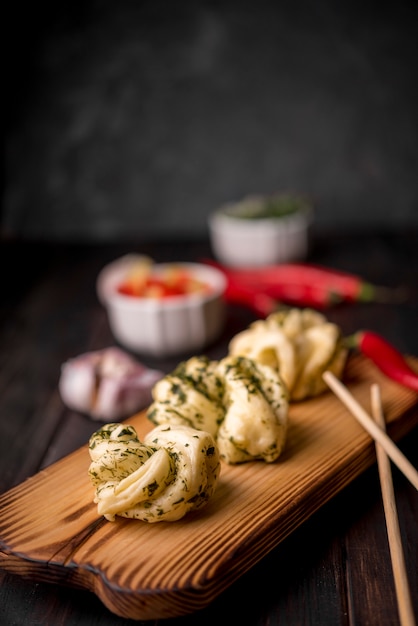 Asiatisches Lebensmittel auf hölzernem Brett mit Knoblauch und Essstäbchen