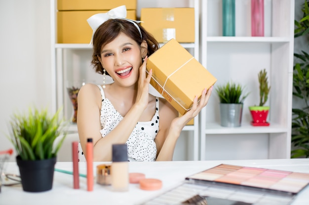 Asiatisches Mädchen, das zu Hause Büro bearbeitet und Paketbriefkasten zum Zustelldienst zum Kunden sortiert