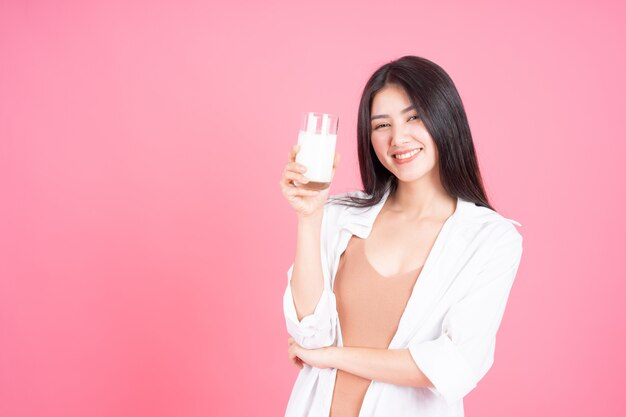 Asiatisches nettes Mädchen der Schönheitsfrau fühlen sich glückliche Trinkmilch für gute Gesundheit morgens auf rosa Hintergrund