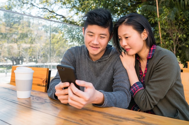 Asiatisches Paar, das das Handy betrachtet.