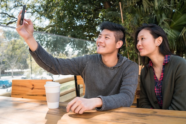 Asiatisches paar, das ein selfie mit handy nimmt.