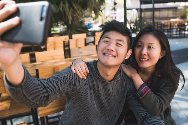 Asiatisches Paar, das ein Selfie mit Handy nimmt.