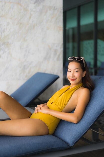 Asiatisches schönes glückliches Lächeln der jungen Frau des Porträts entspannen sich um Swimmingpool im Freien in den Feiertagsferien