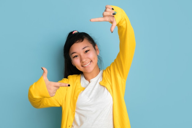 Asiatisches Teenagerporträt lokalisiert auf blauem Studiohintergrund