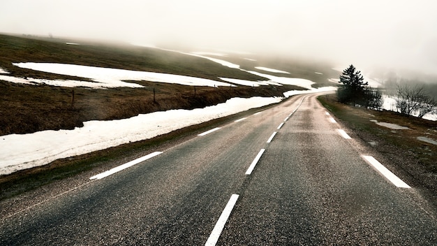 Kostenloses Foto asphaltstraße auf einem mit schnee im winter bedeckten hügel