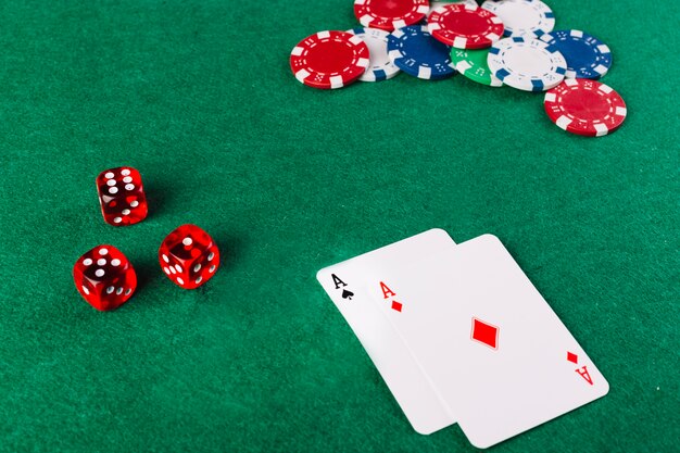 Ass-Spielkarten; Würfel und Chips auf grünem Pokertisch