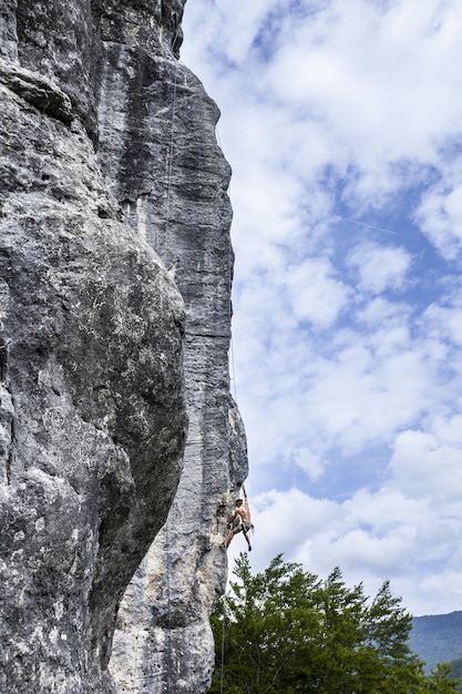 Atemberaubende Aufnahme eines jungen Mannes, der auf den hohen Felsen in Champfromier, Frankreich, klettert