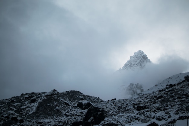 Atemberaubende Aussicht auf den verschneiten Berggipfel bei Nebelwetter