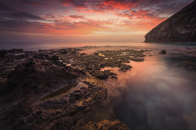 Atemberaubende Aussicht auf die Seelandschaft und die Felsen bei dem malerischen dramatischen Sonnenuntergang