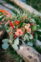 Kostenloses Foto atemberaubende hochzeitsstrauß aus roten blumen und grün liegt o