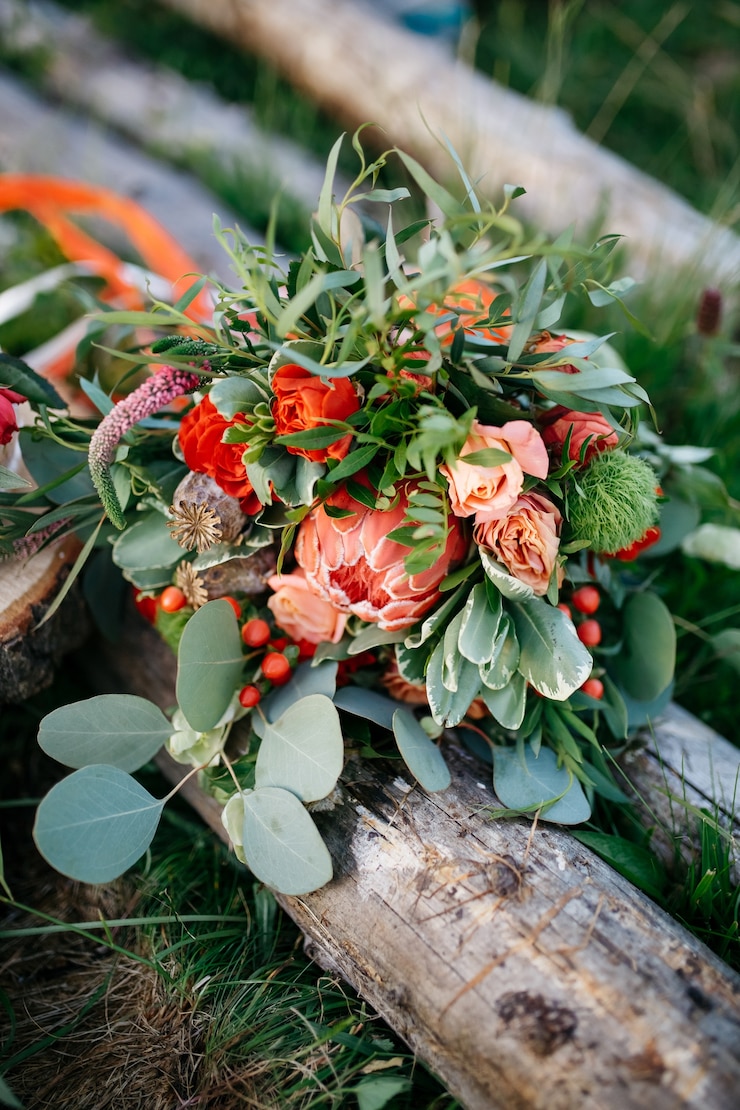 Kostenlose Foto atemberaubende hochzeitsstrauß aus roten blumen und grün liegt o
