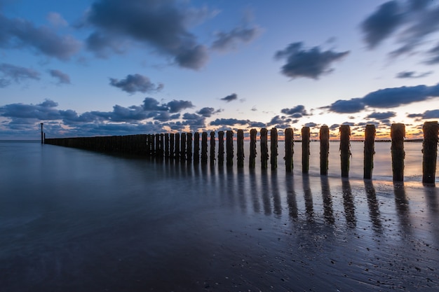 Kostenloses Foto atemberaubende landschaft eines sonnenuntergangs über dem pier des ozeans in westkapelle, zeeland, niederlande