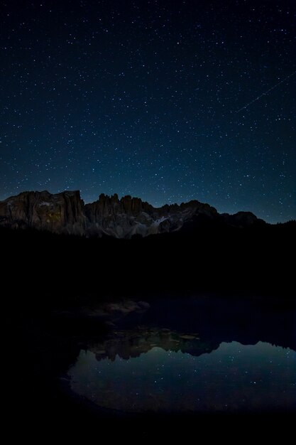 Atemberaubende Landschaft mit Sternenhimmel und felsigen Klippen, die sich nachts auf dem See widerspiegeln