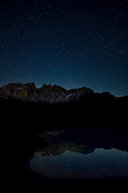 Atemberaubende Landschaft mit Sternenhimmel und felsigen Klippen, die sich nachts auf dem See widerspiegeln