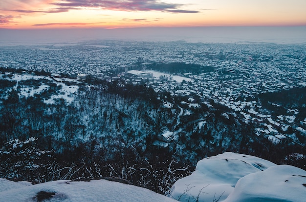 Atemberaubende Sonnenuntergangslandschaft über der Stadt, die im Winter mit Schnee bedeckt ist