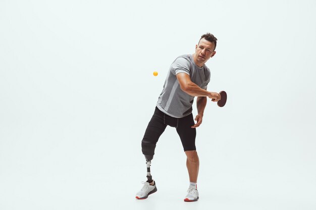 Athlet mit Behinderungen oder Amputierter isoliert auf Weiß. Professioneller männlicher Tennisspieler mit Beinprothesentraining