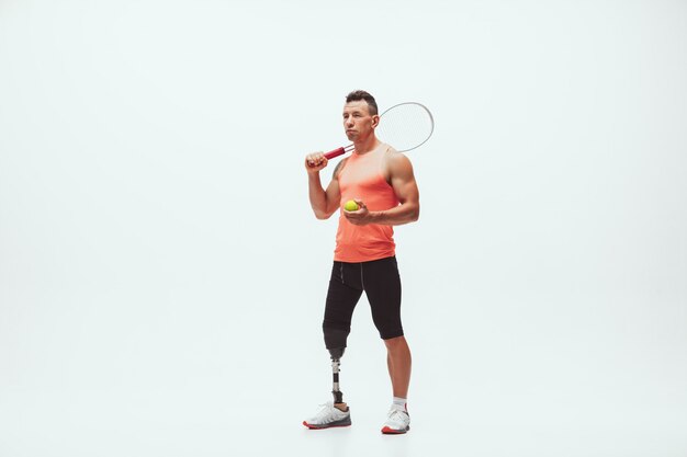 Athlet mit Behinderungen oder Amputierter isoliert auf Weiß. Professioneller männlicher Tennisspieler mit Beinprothesentraining