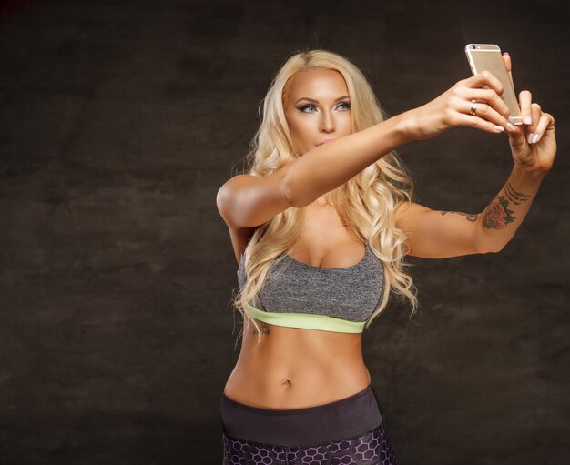 Athletische blonde Frau, die Selfie per Smartphone macht.